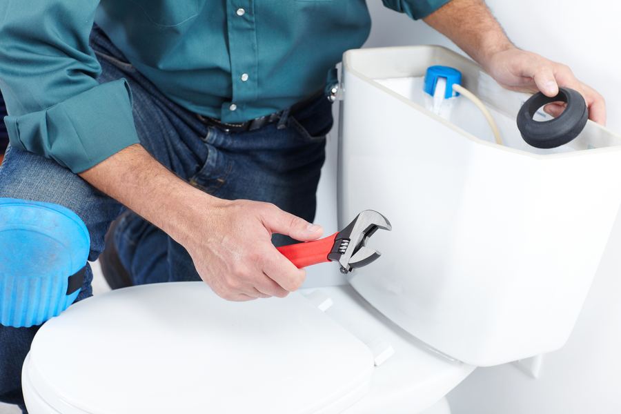 Plumber repairing a toilet tank Plumber repairing a toilet tank